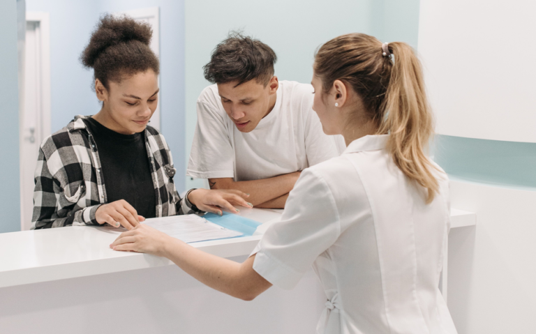 Med spa staff and client reviewing an appointment form at the front desk